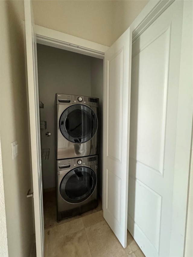 washroom featuring laundry area, stacked washer / dryer, and light tile patterned floors