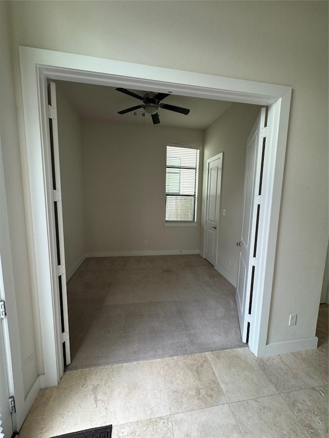unfurnished room with light carpet, baseboards, and a ceiling fan