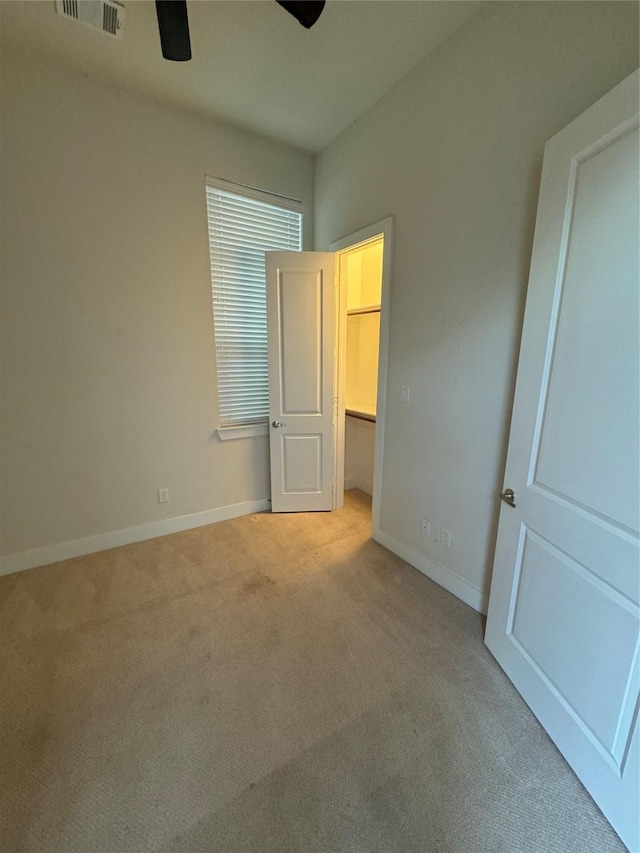 unfurnished bedroom featuring a walk in closet, carpet, baseboards, and visible vents