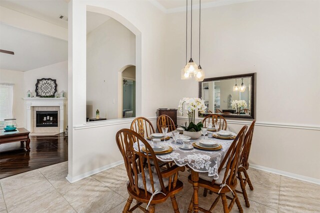 19231 Kelly Pines Ct, Humble, TX 77346 - tiled dining room with a tile fireplace, high vaulted ceiling, crown molding, baseboards, and arched walkways