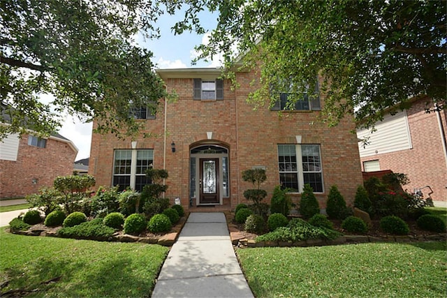 colonial-style house with brick siding and a front yard