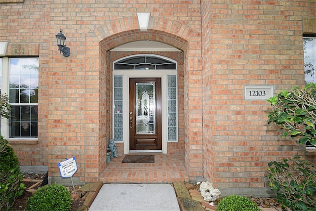 view of exterior entry featuring brick siding