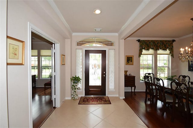 foyer with a notable chandelier, a healthy amount of sunlight, and crown molding