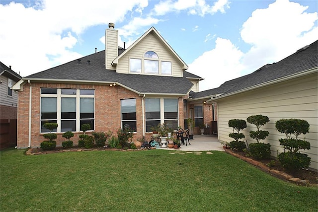 back of house featuring brick siding, a chimney, a lawn, and a patio