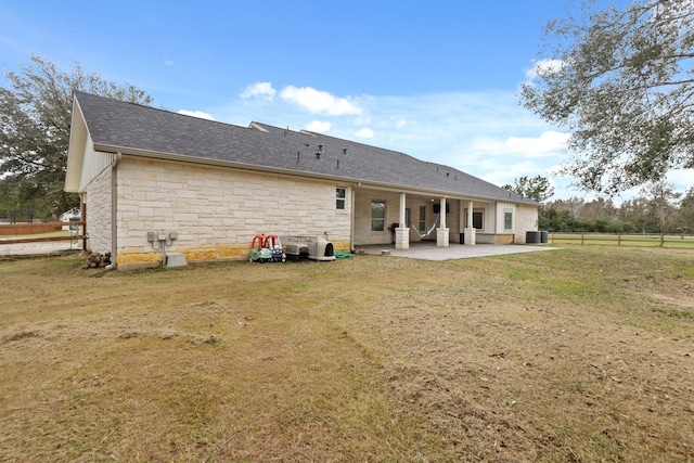 19503 Fisher Dr, Tomball, TX 77377 - back of house with roof with shingles, a patio area, stone siding, central AC, and a yard