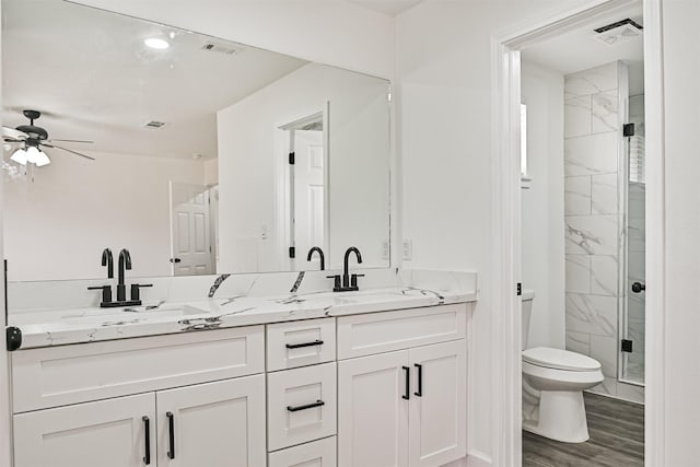 512 Stoneledge Dr, Friendswood, TX 77546 - bathroom featuring toilet, double vanity, ceiling fan, a marble finish shower, and wood finished floors