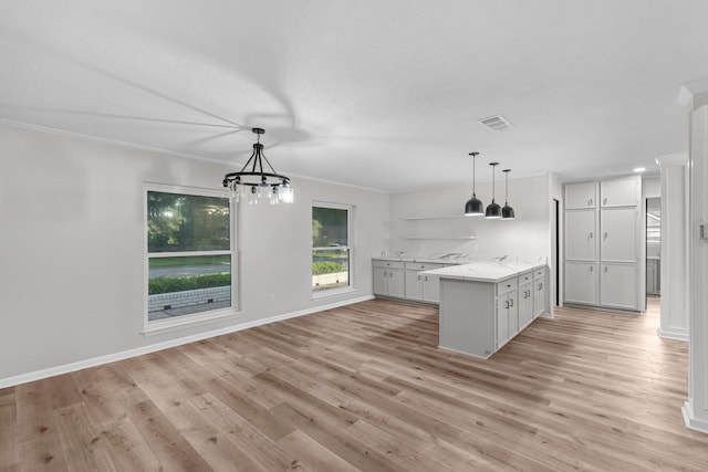 213 Westview Dr, Sealy, TX 77474 - kitchen with light wood-type flooring, ornamental molding, hanging light fixtures, a chandelier, and white cabinetry