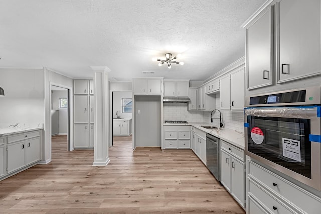 213 Westview Dr, Sealy, TX 77474 - kitchen with appliances with stainless steel finishes, light wood-style floors, tasteful backsplash, under cabinet range hood, and a textured ceiling