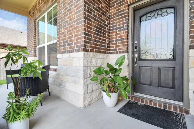 view of exterior entry featuring brick siding and covered porch