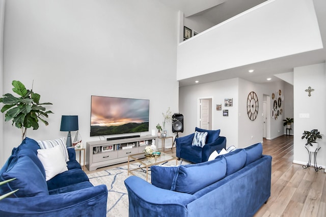 living room with wood finished floors, baseboards, a high ceiling, and recessed lighting