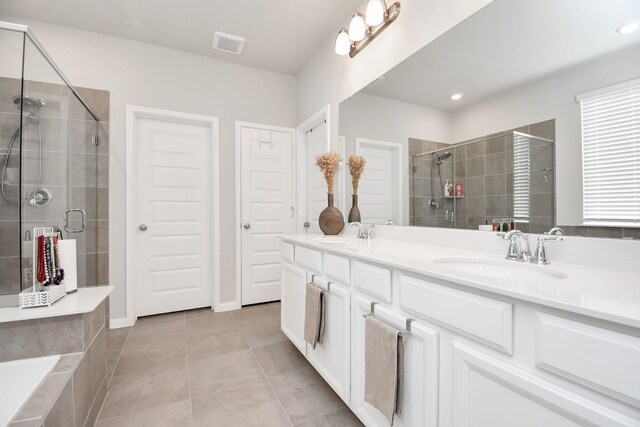 bathroom with a sink, double vanity, a shower stall, and tile patterned floors