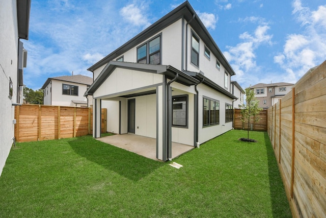 rear view of property with a yard, a patio, stucco siding, and a fenced backyard