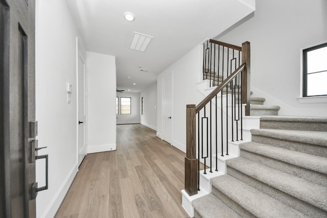 staircase with wood finished floors, baseboards, and recessed lighting