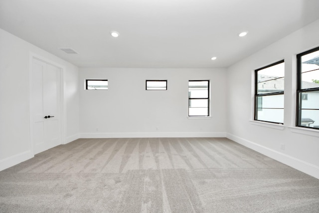 unfurnished room featuring light colored carpet, visible vents, baseboards, and recessed lighting