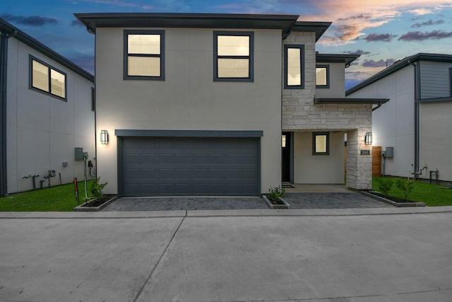 view of front of property with stone siding, stucco siding, driveway, and an attached garage