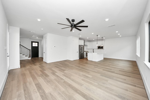 unfurnished living room featuring visible vents, recessed lighting, light wood-style flooring, a ceiling fan, and baseboards