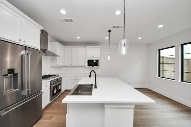 kitchen featuring a sink, wall chimney exhaust hood, stainless steel appliances, visible vents, and tasteful backsplash