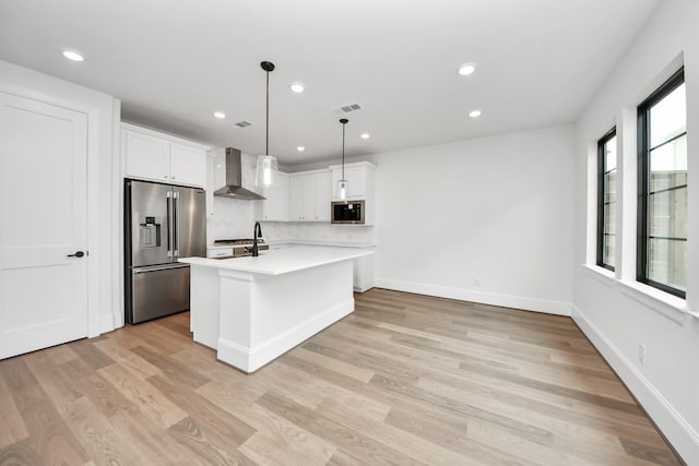 kitchen featuring recessed lighting, wall chimney exhaust hood, light countertops, built in microwave, and high end refrigerator