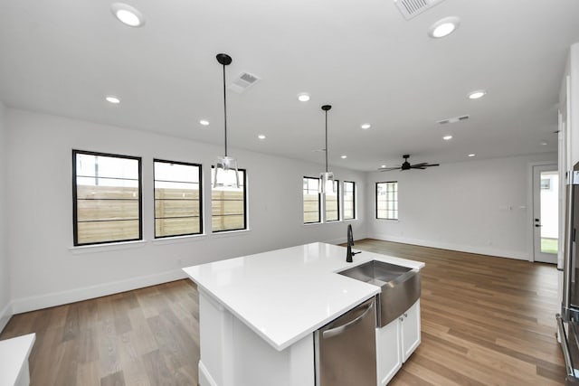 kitchen featuring stainless steel dishwasher, baseboards, open floor plan, and a sink