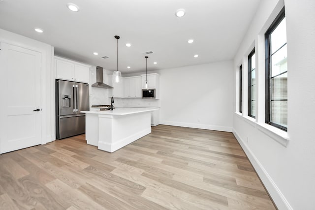 kitchen with recessed lighting, light countertops, appliances with stainless steel finishes, and wall chimney exhaust hood