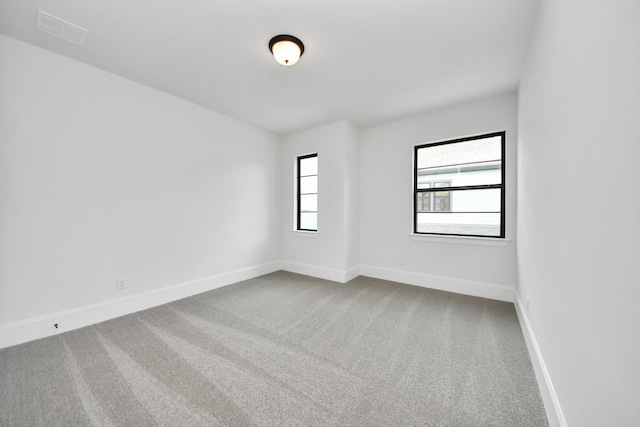 empty room featuring visible vents, baseboards, and carpet floors