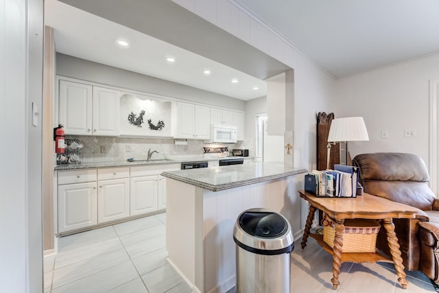 kitchen with electric range, white microwave, decorative backsplash, white cabinets, and light stone countertops