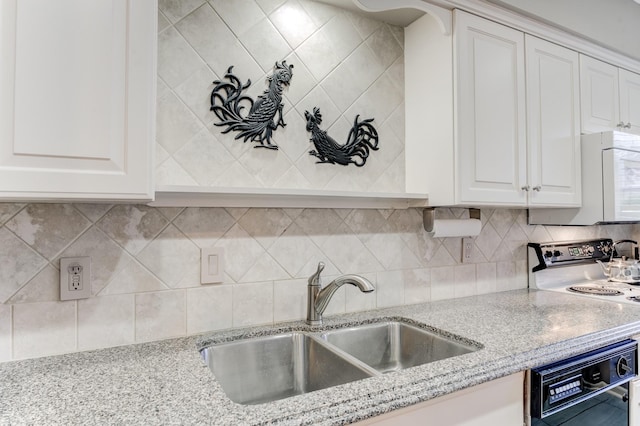 kitchen with a sink, black dishwasher, white microwave, light stone counters, and white cabinets