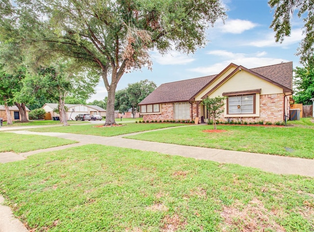 view of front of property featuring a shingled roof, brick siding, fence, and a front yard