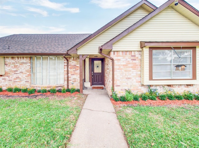 ranch-style home featuring roof with shingles, a front lawn, and brick siding