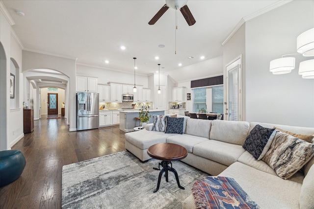 living area with ornamental molding, dark wood-type flooring, recessed lighting, ceiling fan, and arched walkways