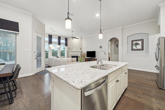 kitchen featuring a sink, stainless steel appliances, ceiling fan, arched walkways, and baseboards