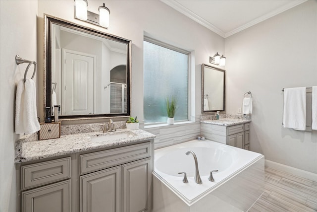 bathroom featuring a garden tub, a sink, two vanities, a shower stall, and ornamental molding