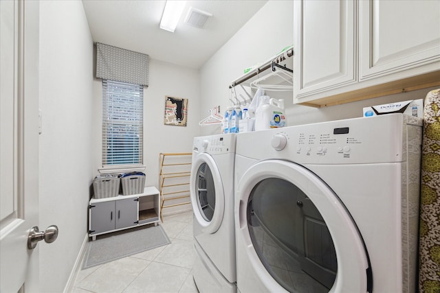 washroom featuring washer and clothes dryer, cabinet space, visible vents, light tile patterned floors, and baseboards
