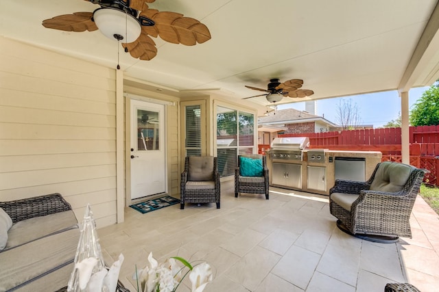 view of patio with area for grilling, an outdoor kitchen, fence, and a ceiling fan