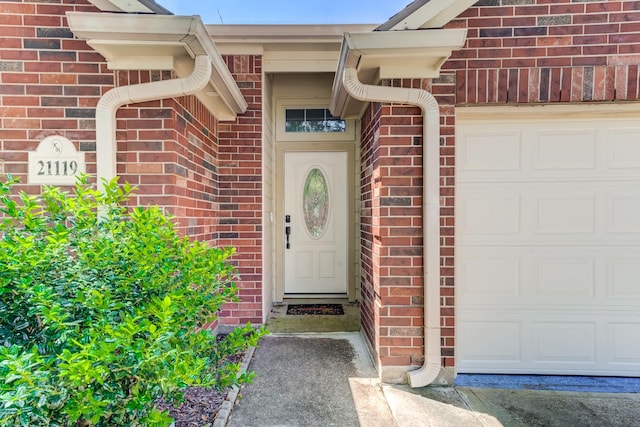 doorway to property featuring brick siding and a garage