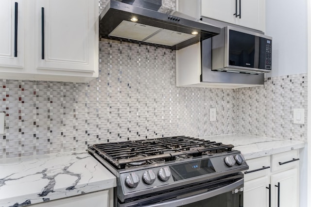 kitchen with stainless steel appliances, wall chimney range hood, light stone counters, decorative backsplash, and white cabinets