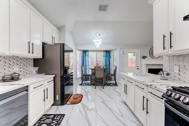 kitchen featuring white cabinets, visible vents, black appliances, vaulted ceiling, and marble finish floor