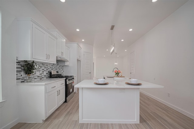 7307 W Knoll St, Houston, TX 77028 - kitchen featuring under cabinet range hood, white cabinets, light wood-style floors, and gas stove