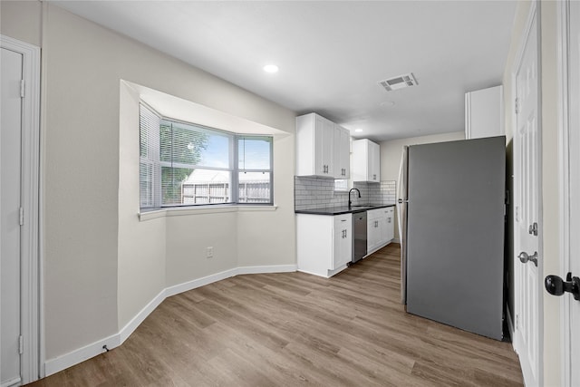 6727 Winding Trace Dr, Houston, TX 77086 - kitchen featuring appliances with stainless steel finishes, a sink, dark countertops, white cabinets, and light wood-type flooring