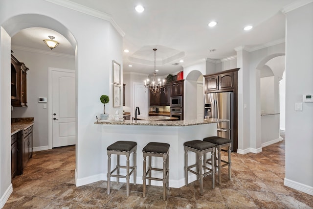 8483 Majestic Lake Ct, Montgomery, TX 77316 - kitchen featuring a breakfast bar area, dark brown cabinetry, baseboards, arched walkways, and appliances with stainless steel finishes