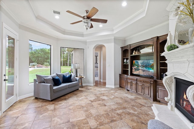 8483 Majestic Lake Ct, Montgomery, TX 77316 - living room featuring visible vents, baseboards, a raised ceiling, arched walkways, and a high end fireplace