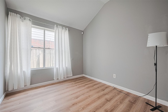 unfurnished room with lofted ceiling, baseboards, and light wood finished floors