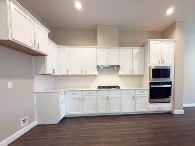 1111 Robbie St, Houston, TX 77009 - kitchen featuring stainless steel appliances, baseboards, under cabinet range hood, dark wood-style flooring, and recessed lighting