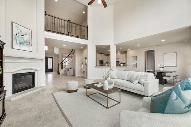 18538 Wade Creek Ln, Cypress, TX 77433 - living area with stone finish floor, stairway, a towering ceiling, ceiling fan, and a high end fireplace
