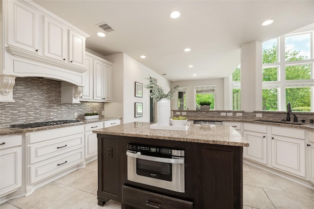 18538 Wade Creek Ln, Cypress, TX 77433 - kitchen with a sink, tasteful backsplash, stainless steel gas stovetop, visible vents, and light tile patterned floors