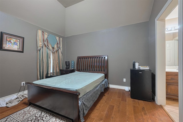 7611 Herndon Pl, Sugar Land, TX 77479 - bedroom with wood finished floors, baseboards, vaulted ceiling, and ensuite bathroom
