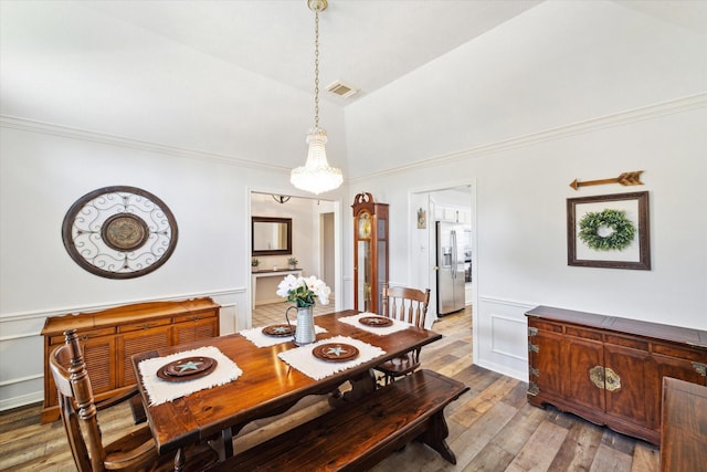 2419 Londonderry Dr, Pearland, TX 77581 - dining area featuring light wood-type flooring, a chandelier, ornamental molding, high vaulted ceiling, and wainscoting