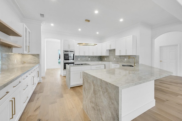 686 Edgewood Dr, Montgomery, TX 77356 - kitchen featuring a sink, stainless steel double oven, light stone countertops, arched walkways, and ornamental molding