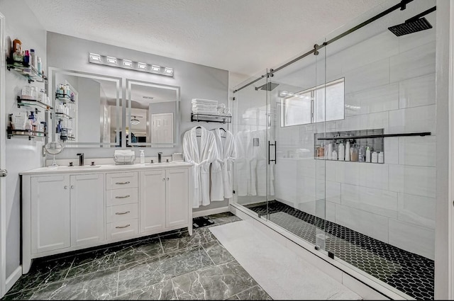 16107 Lakestone Dr, Tomball, TX 77377 - bathroom featuring a stall shower, double vanity, marble finish flooring, a textured ceiling, and baseboards