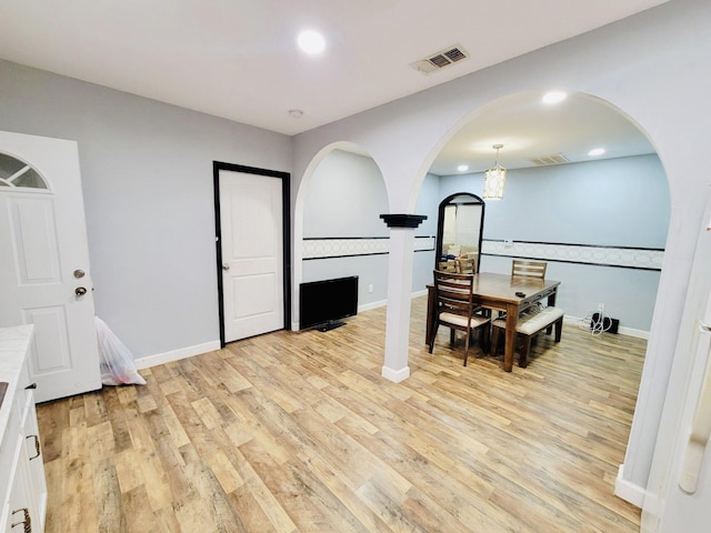 dining room with arched walkways, recessed lighting, light wood finished floors, and visible vents